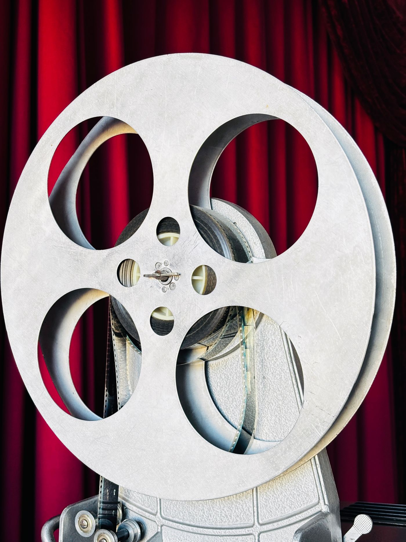 Vintage film reel against red theatre curtains